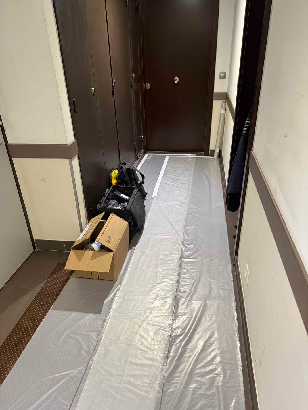 Couloir de l’immeuble protégé par un film de chantier avant l’intervention